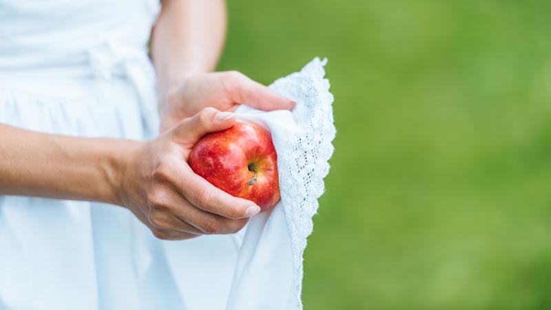 girl wiping red apple with apron