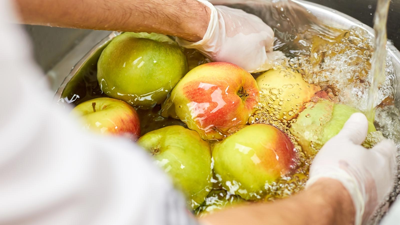 many apples washing in a metal bowl